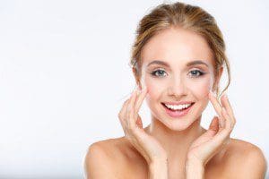 Young woman touching her face isolated on white background .