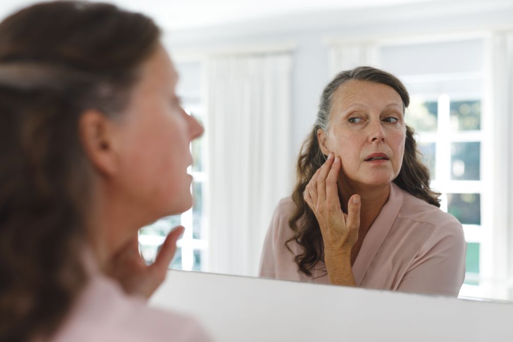 older white woman look at face in mirror