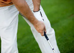 A man holding a golf club on the grass.