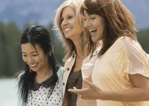 Three women laughing and talking to each other.