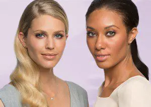 Two women posing for a picture in front of a purple background.