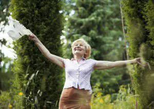 A woman in the woods holding her arms up.