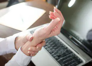 A person holding their hands in front of a laptop.