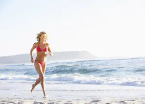 A woman in a bikini running on the beach.