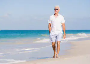 A man walking on the beach in shorts