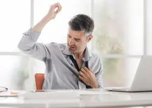 A man adjusts his tie while sitting at the table.