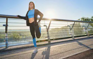 A woman stretching on the side of a bridge.