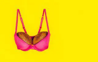 A pink bra with two pieces of bread in it.