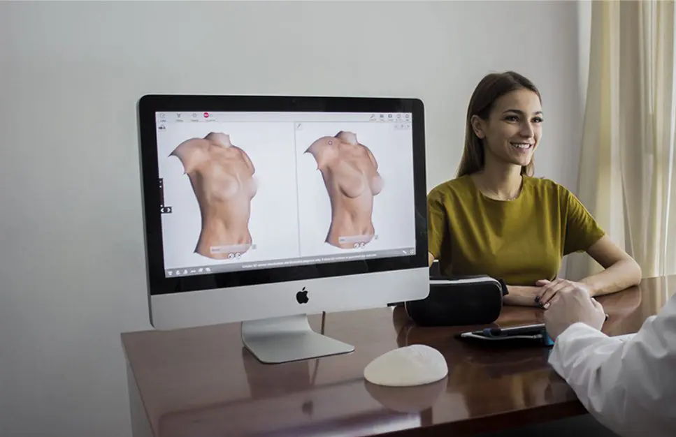 A woman sitting at her desk with an apple computer.