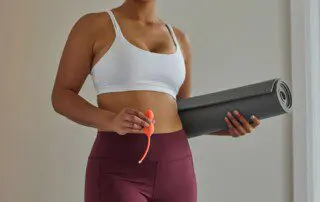 Woman holding yoga mat and ben wa balls.