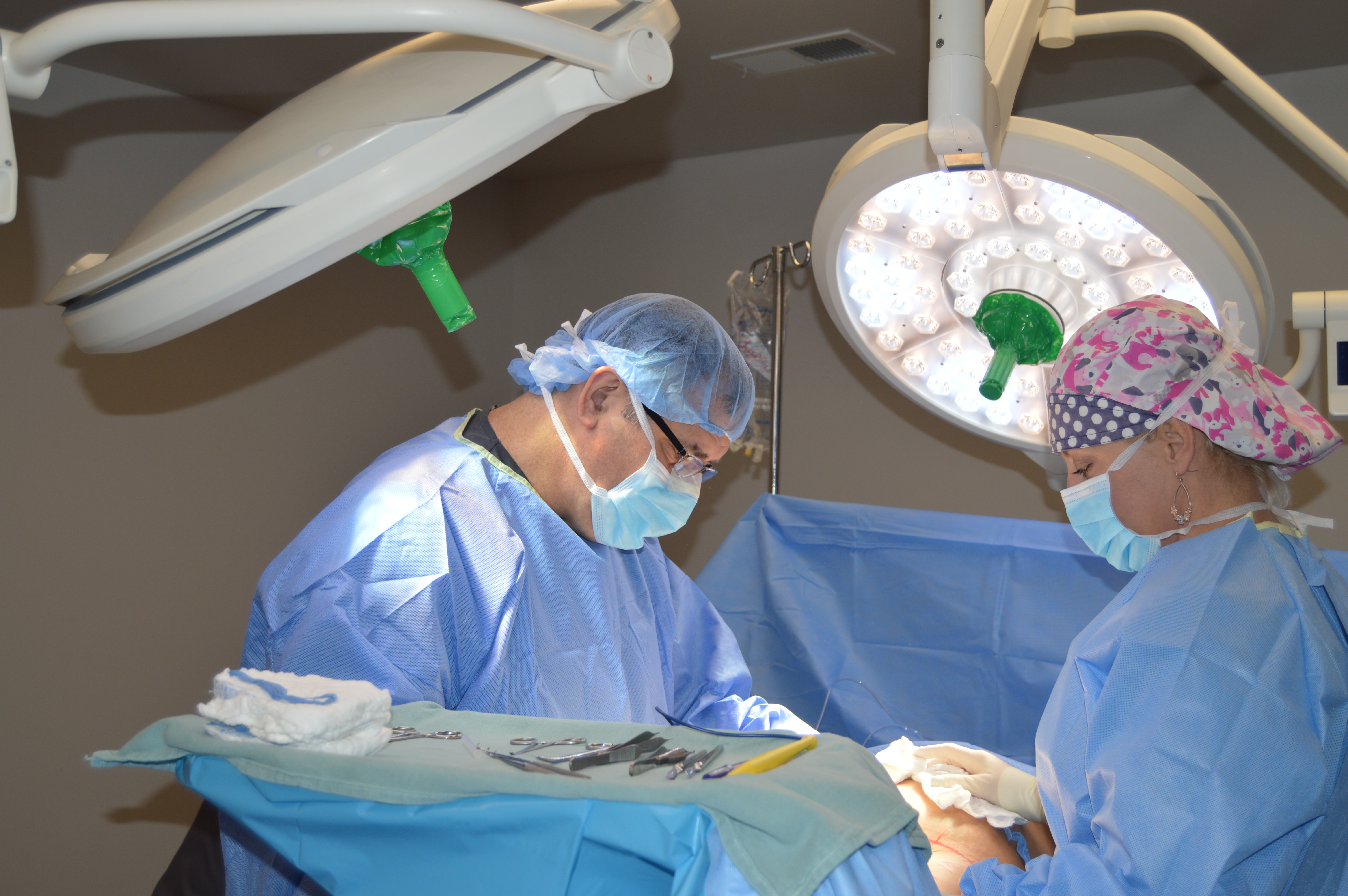 Two surgeons in a room with lights and equipment.